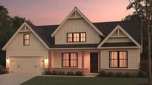 Modern farmhouse style house with warm lights at sunset and a two-car garage on a green lawn