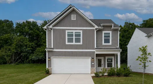Modern two-story gray house with white garage door and concrete driveway under blue sky.
