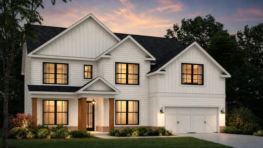Modern white two-story house with large windows, a garage, and warm interior lighting at sunset.
