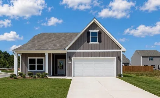 Modern gray house with white garage door, front porch, manicured lawn, and clear blue sky with clouds.
